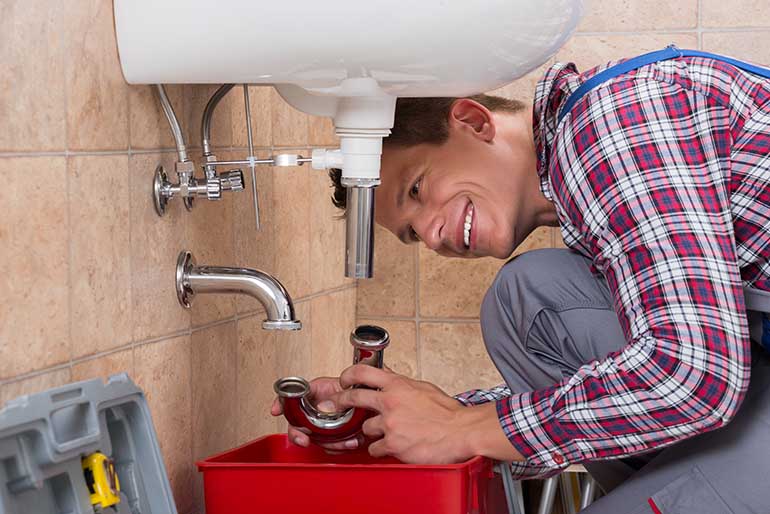 A Matheson plumber repairing a sink pipe